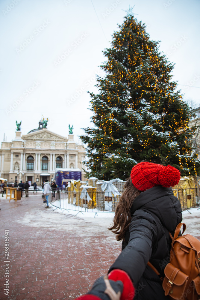 follow me concept woman holding hand boyfriend christmas tree on background at central city square