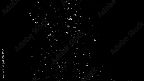 Blurry images of soda water bubbles splashing and floating up to top of water surface which little and big circle texture shaped up by gas power in carbonate drink make refreshing moment on black