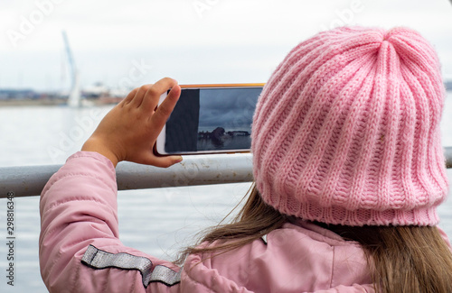 a little girl takes photos with her phone of the sea