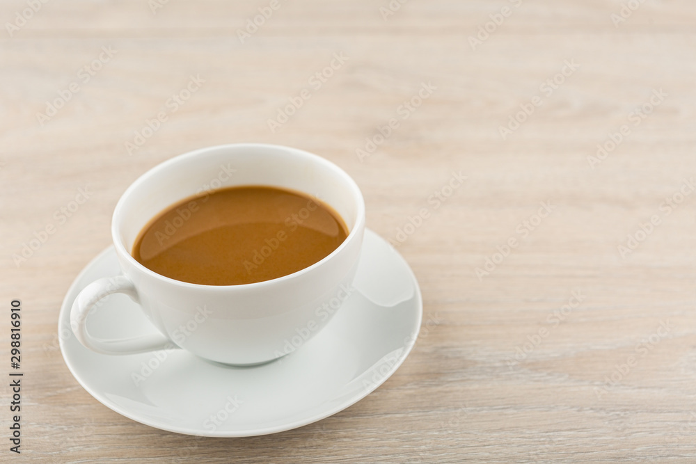 Coffee in a white cup placed on a wooden table Coffee in a white cup placed on a wooden table