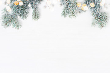 White wooden background decorated wit h frosty fir branches and lights, Christmas of New Year holiday frame