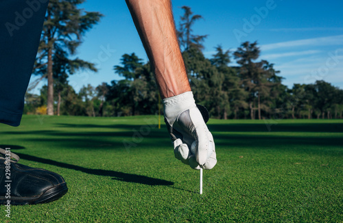 Golfer puts the golf ball on a tee