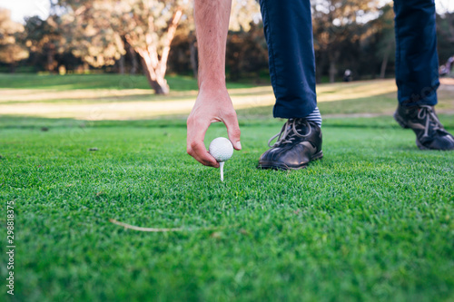 Golfer puts the golf ball on a tee