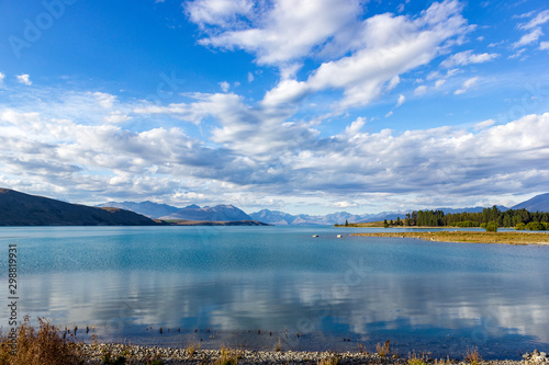 Beautiful Lake Tekapo with mountain range in the Background on a sunny day with withe clouds, South Island, New Zealand