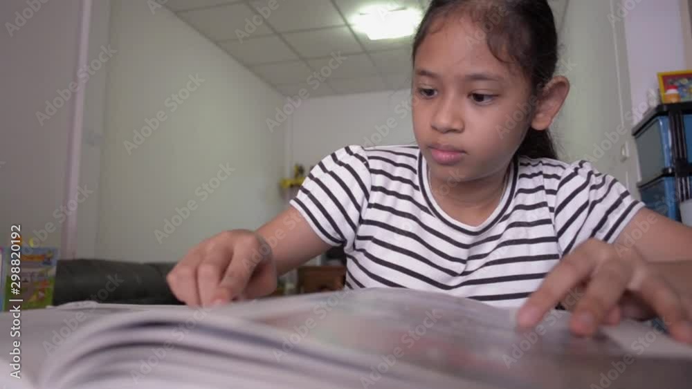 Cute asian girl reading a book on the desk at home. Education concept. Cute asian girl reading a book on the desk at home. Education concept.