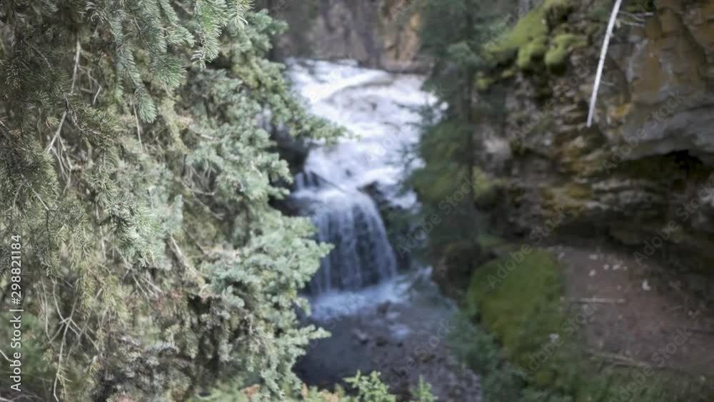 Reveal pan of powerful cascading small waterfall in Johnston Canyon, rack focus change on a sunny summer day overcast 24fps 1080p full hd Reveal pan of powerful cascading small waterfall in Johnston Canyon, rack focus change on a sunny summer day overcast 24fps 1080p full hd