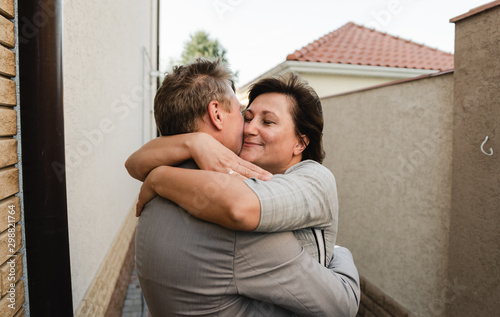 Happy adult couple embracing and sharing time together near their house. Elegant mature people celebrating anniversary. Love concept and relationship lifestyle