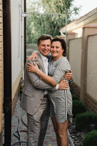 Happy adult couple embracing and sharing time together near their house. Elegant mature people celebrating anniversary. Love concept and relationship lifestyle © Vadym