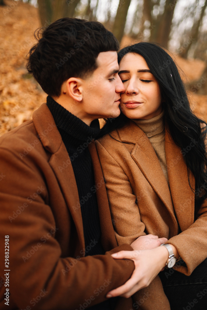 Obraz premium Stylish young couple outdoors on a beautiful autumn day in the forest. Young couple in love holding hands and walking through a park on a autumn day. The concept of youth, love and lifestyle.