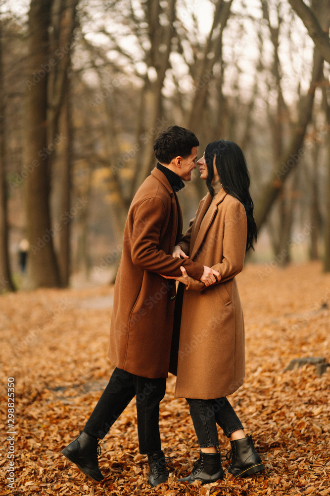 Stylish young couple outdoors on a beautiful autumn day in the forest. Young couple in love holding hands and walking through a park on a autumn day. The concept of youth, love and lifestyle. Stylish young couple outdoors on a beautiful autumn day in the forest. Young couple in love holding hands and walking through a park on a autumn day. The concept of youth, love and lifestyle.