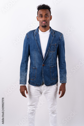 Young bearded African man wearing denim jacket against white bac