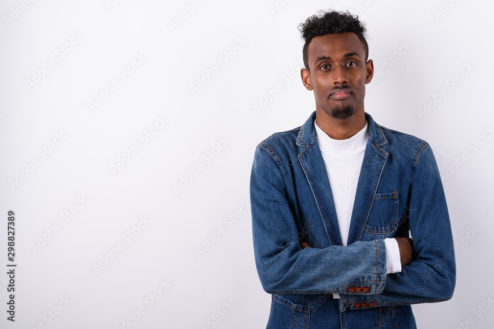 Fototapeta premium Young bearded African man wearing denim jacket against white bac