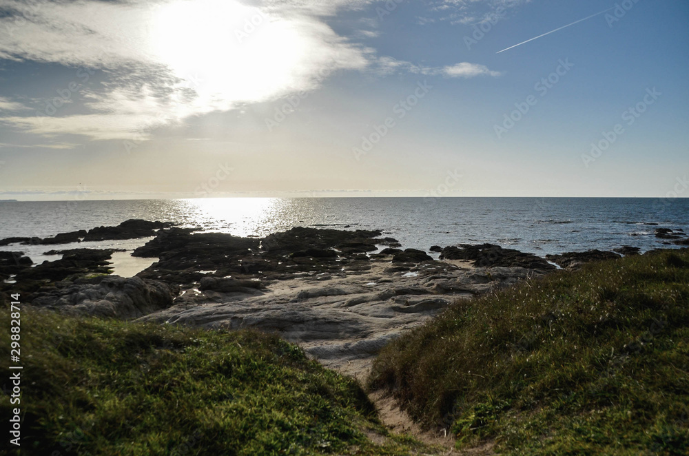 Sunset view on Atlantic shore beach. Path with green grass