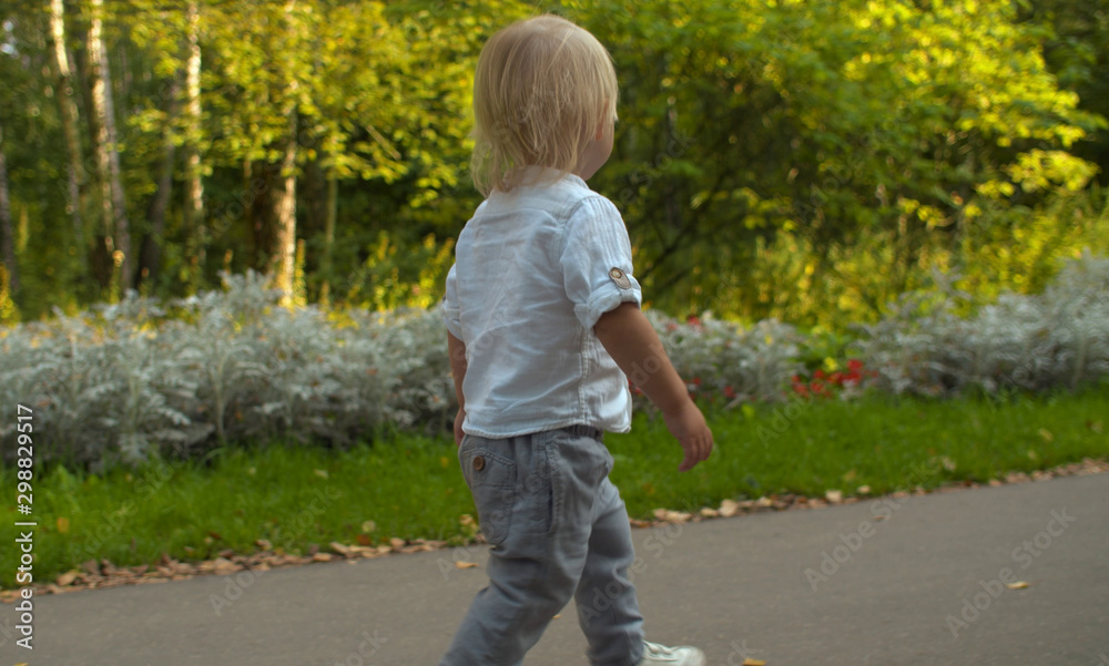 Cute toddler walking along the road in the park Cute toddler walking along the road in the park