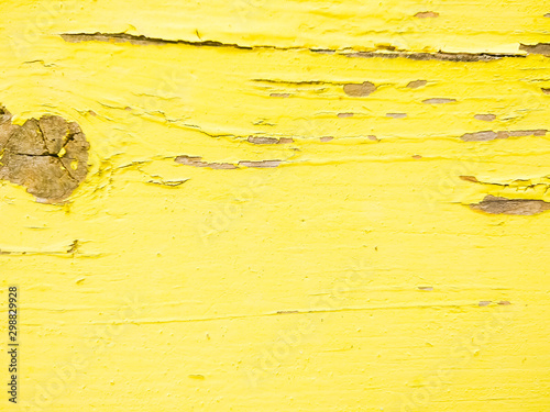 Wood texture with yellow flaked paint. Peeling paint on weathered wood. Old cracked paint pattern on rusty background. Chapped paint on an old wooden surface
