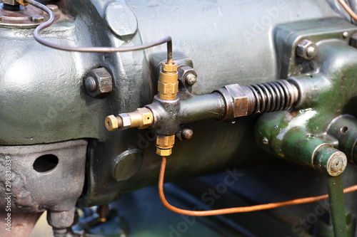 Partial view of an old tractor. A detail view of an hydraulic valve of the motor of an historical tractor.