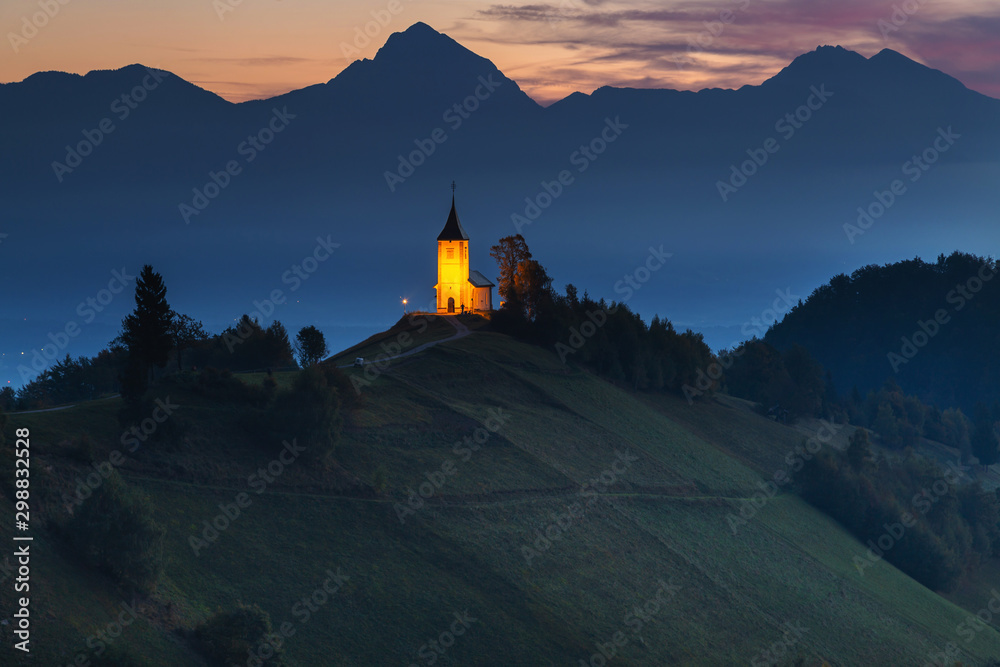 Obraz premium Autumn landscape of a beautiful church on the top of a hill, in Slovenia