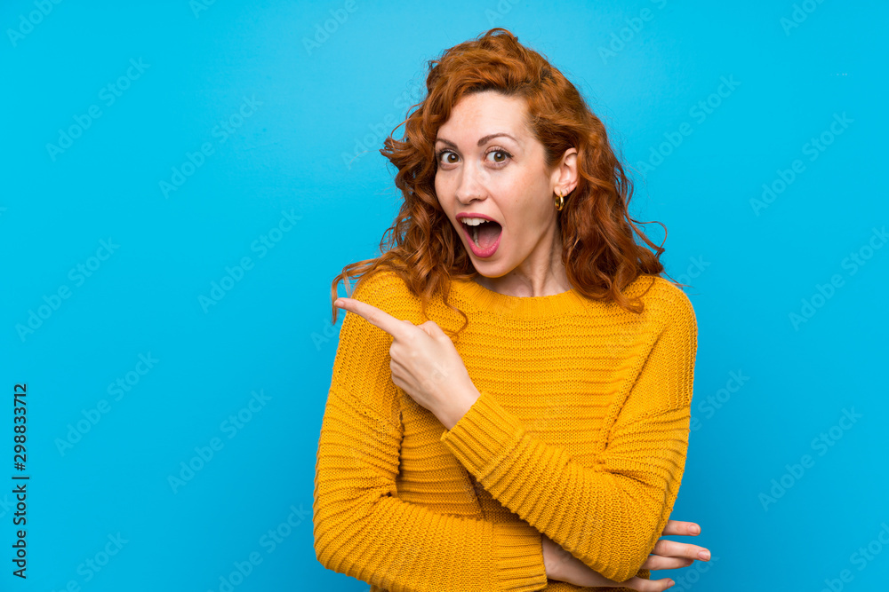 Redhead woman with yellow sweater surprised and pointing side Redhead woman with yellow sweater surprised and pointing side