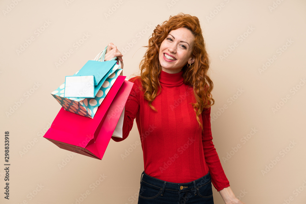 Fototapeta premium Redhead woman with turtleneck sweater holding a lot of shopping bags