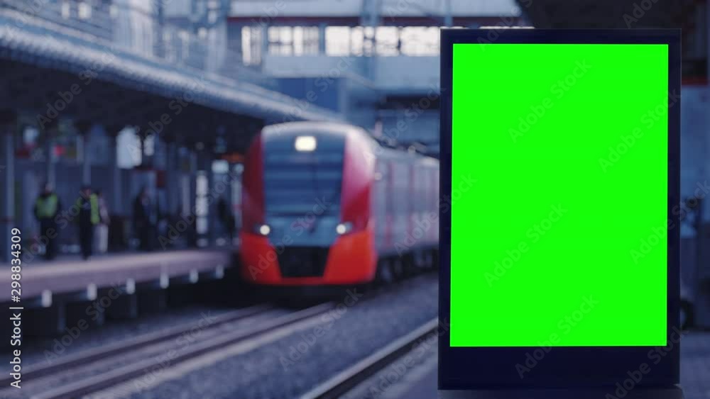  Empty modern billboard with a green screen for advertising, on a train station, blank billboard on subway station opposite the train arriving at the platform
