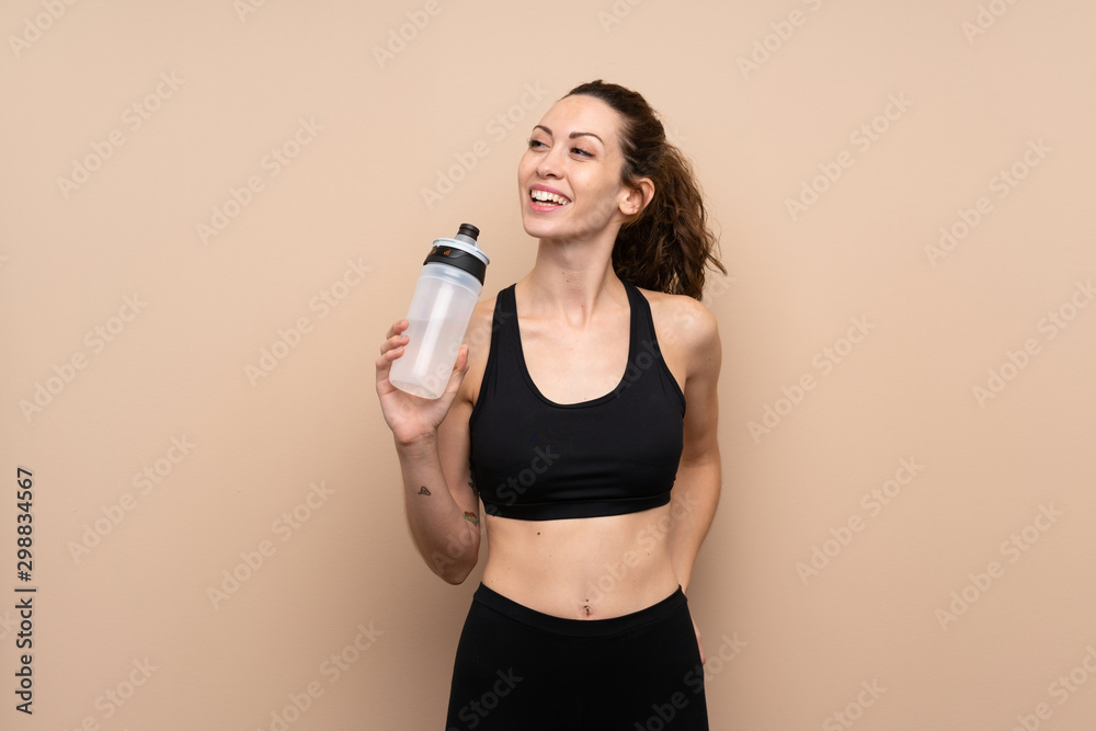 Young sport woman over isolated background with sports water bottle Young sport woman over isolated background with sports water bottle