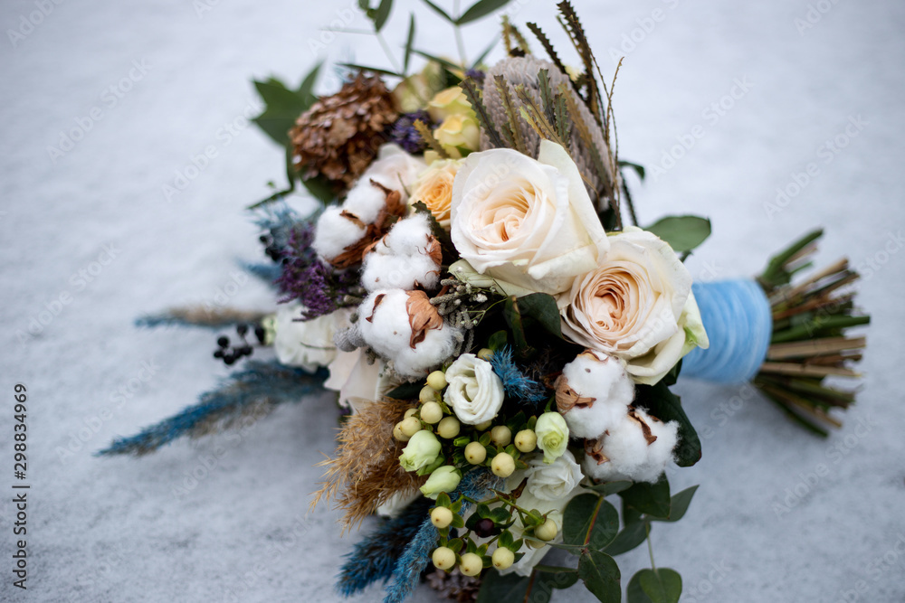 bridal bouquet of roses and cotton flowers in the snow