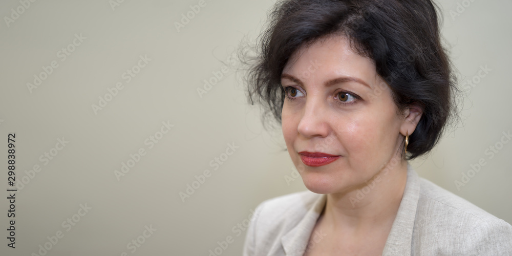 Attractive middle-aged successful women with beautiful smile in business suit against concrete beige wall, head and shoulders portrait with copy space. Attractive middle-aged successful women with beautiful smile in business suit against concrete beige wall, head and shoulders portrait with copy space.