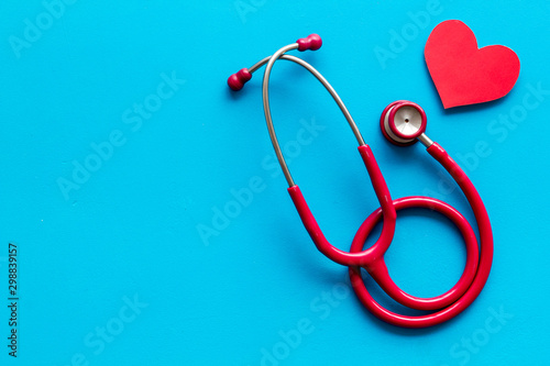 Health care concept. Heart icon and stethoscope on blue background top view copy space