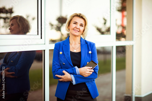 business portrait of a woman Director, with a phone, in a blue jacket on the street photo