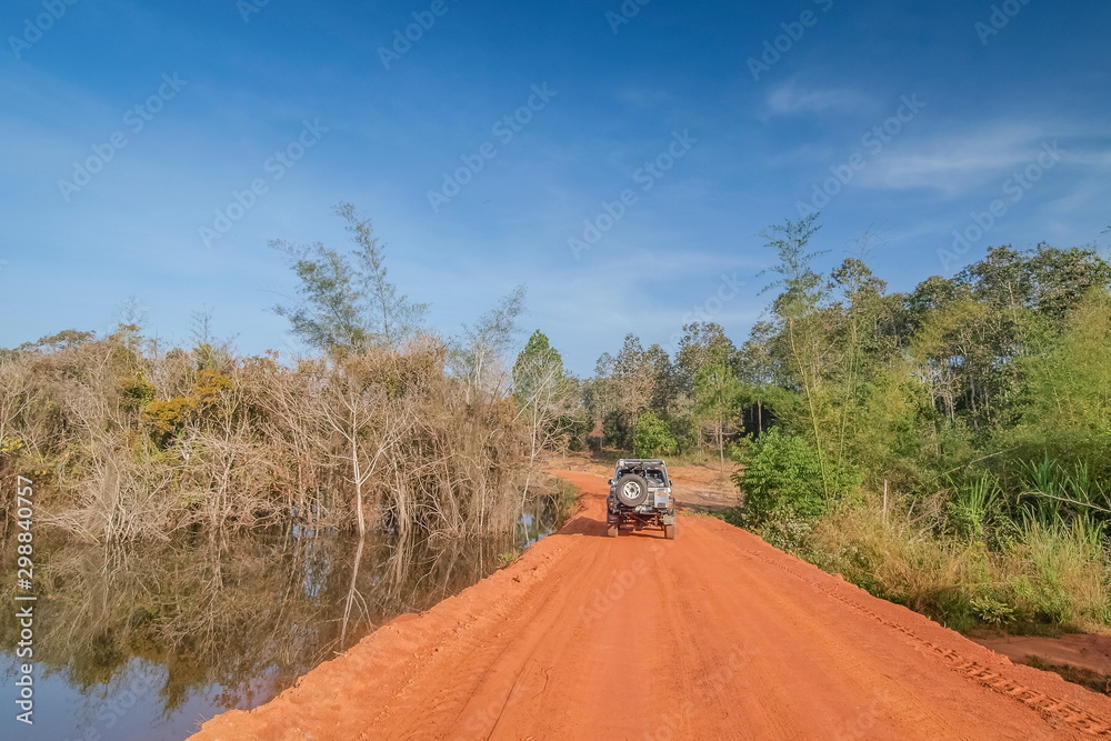 view of a 4wd. truck parking on dirt road around with green grass, swamp and blue sky background, adventure in Thung Salang Luang National Park, Phetchabun, Thailand.