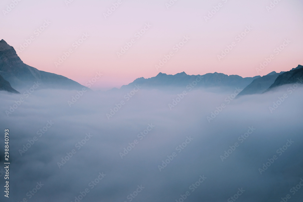 Mountain peaks covered with clouds during sunset.