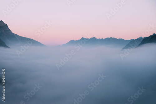 Mountain peaks covered with clouds during sunset. © Iryna
