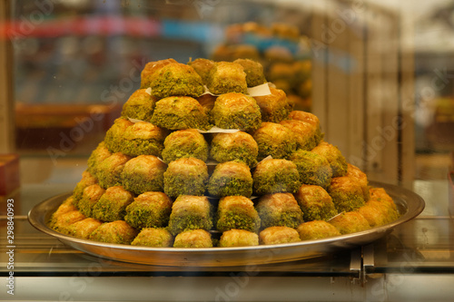A tray of traditional Turkish dessert Baklava made with pistachio between very thin sheets of dough on a store display.