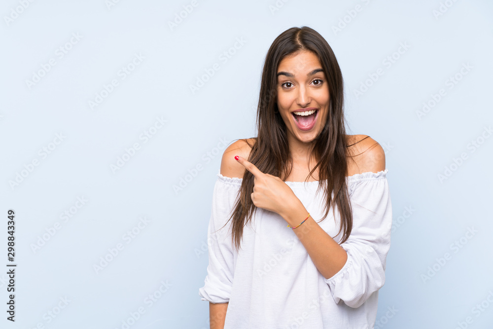 Young woman over isolated blue background pointing finger to the side Young woman over isolated blue background pointing finger to the side