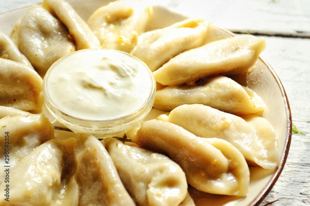 Dumplings in a beautiful plate. Dumplings on a wooden background. Wooden table background with autumn leaves. Appetizing little pie with filling. Traditional homemade food. Dumplings in a beautiful plate. Dumplings on a wooden background. Wooden table background with autumn leaves. Appetizing little pie with filling. Traditional homemade food.