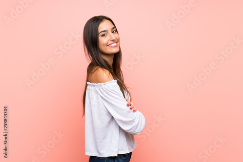 Young woman over isolated pink background with arms crossed and looking forward