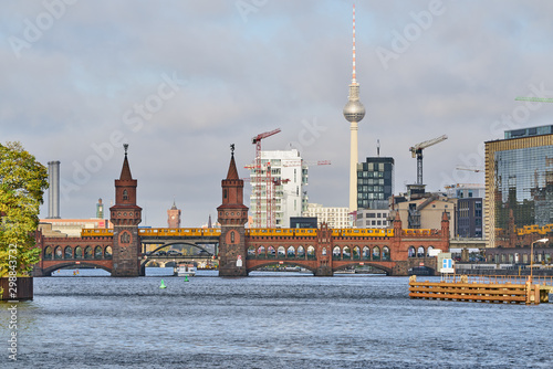 Die Berliner Oberbaumbrücke überspannt die Spree im Morgenlicht mit dem Rathaus, dem Fernsehturm und mehreren Baukränen im Hintergrund