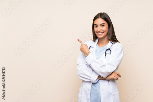 Fototapeta Young doctor woman over isolated background pointing finger to the side