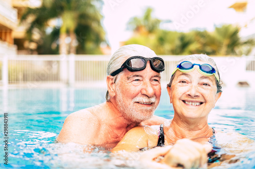 couple of two seniors hugged in the water of swimming pool - active man and woman doing exercise together at the pool - hugged with love © Daniel