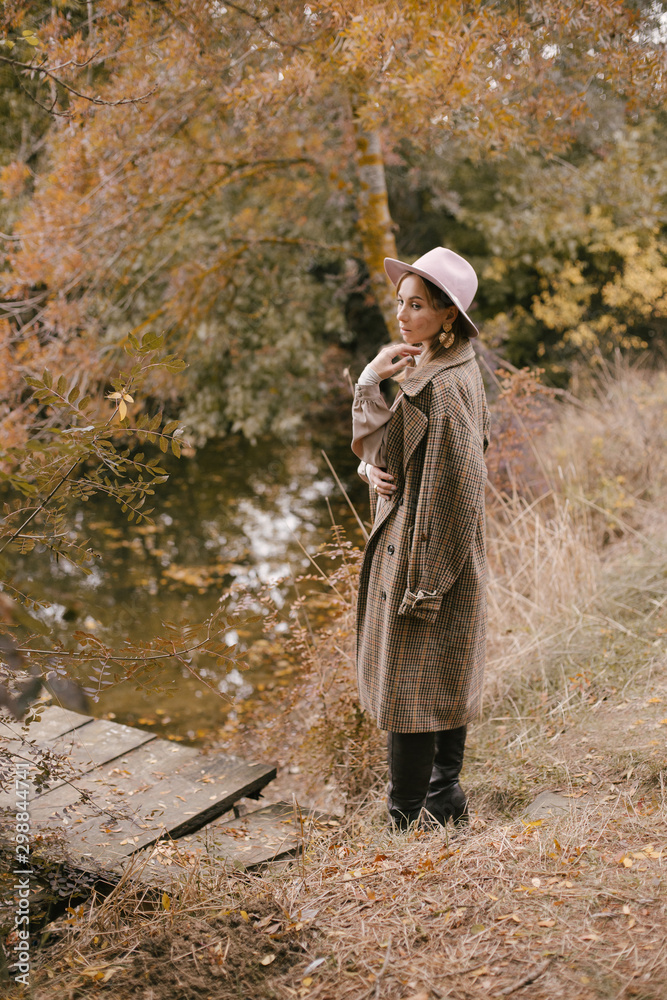 Woman in fashion clothes posing in autumn forest.