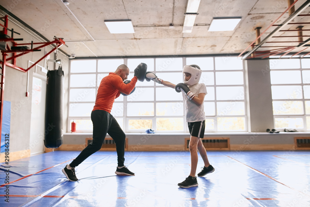 Fototapeta premium boy learning kickboxing with his father at sport center, full length side view photo. ccopy space. health and body care