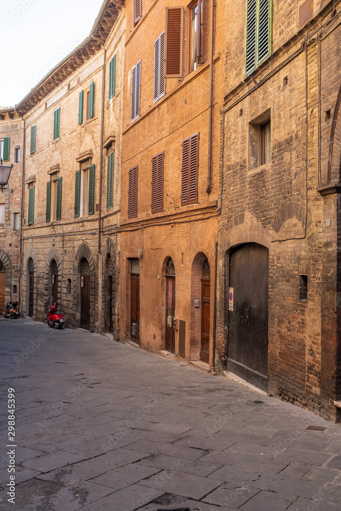 An empty back street of Siena, with a buildings that curve into the distance