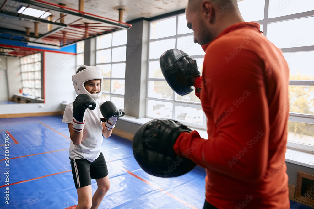 little smiling boxer is fond of fighting with coach, close up photo. little smiling boxer is fond of fighting with coach, close up photo.
