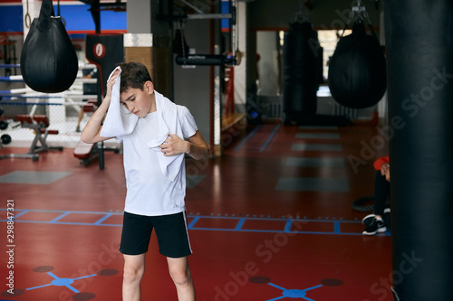 young boxer wiping his forehead after workout at sport center close up photo. copy space.