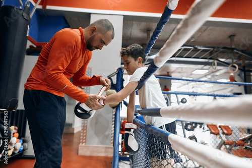 young handsome man helping kid to wear gloves, put on gloves. close up side view photo.