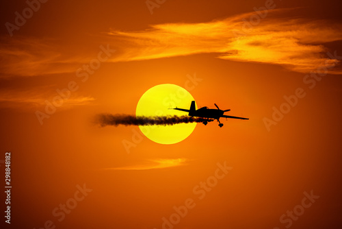 Plane gliding in front of the setting sun at an airshow. photo
