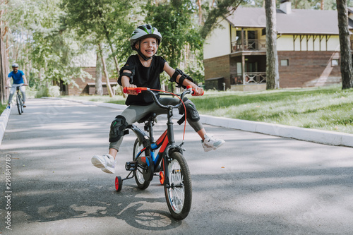 Cheerful little girl in helmet riding bicycle outdoors