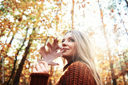 Beautiful woman holding autumnal leaf