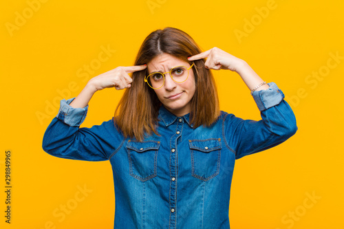 Фотография young pretty woman with a serious and concentrated look, brainstorming and think
