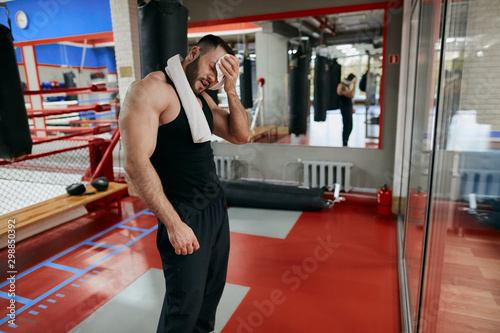 tired sporty man wiping his forehead, sportsman looks exhausted after training for a long time. tiredness